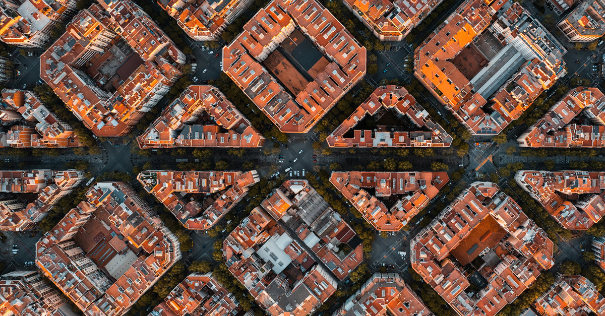 Bird's-eye view of a dense urban area with tightly packed red-roofed buildings and intersecting streets.