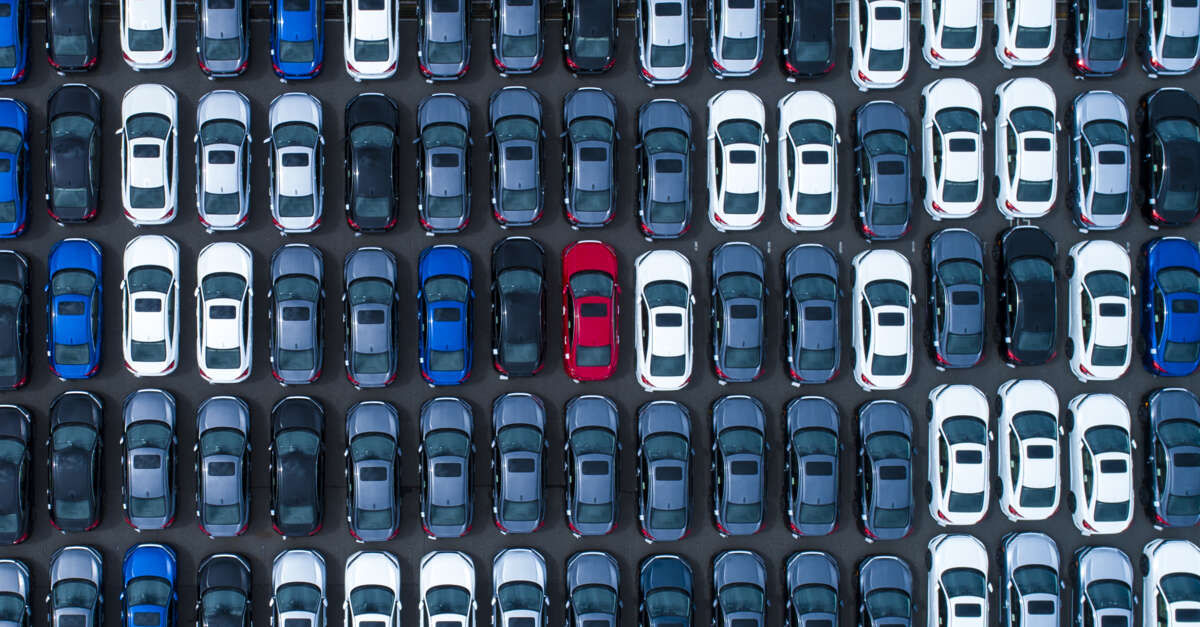 aerial stock imagery of packed car lot with red car in the middle